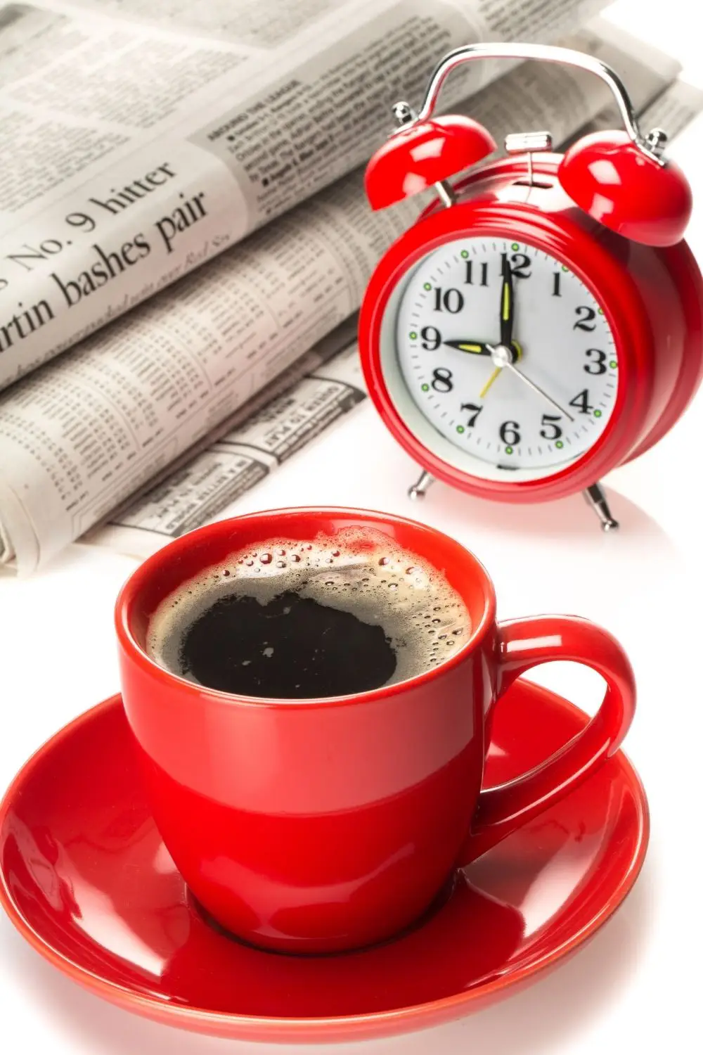 A cup of coffee sits next to a clock for intermittent fasting