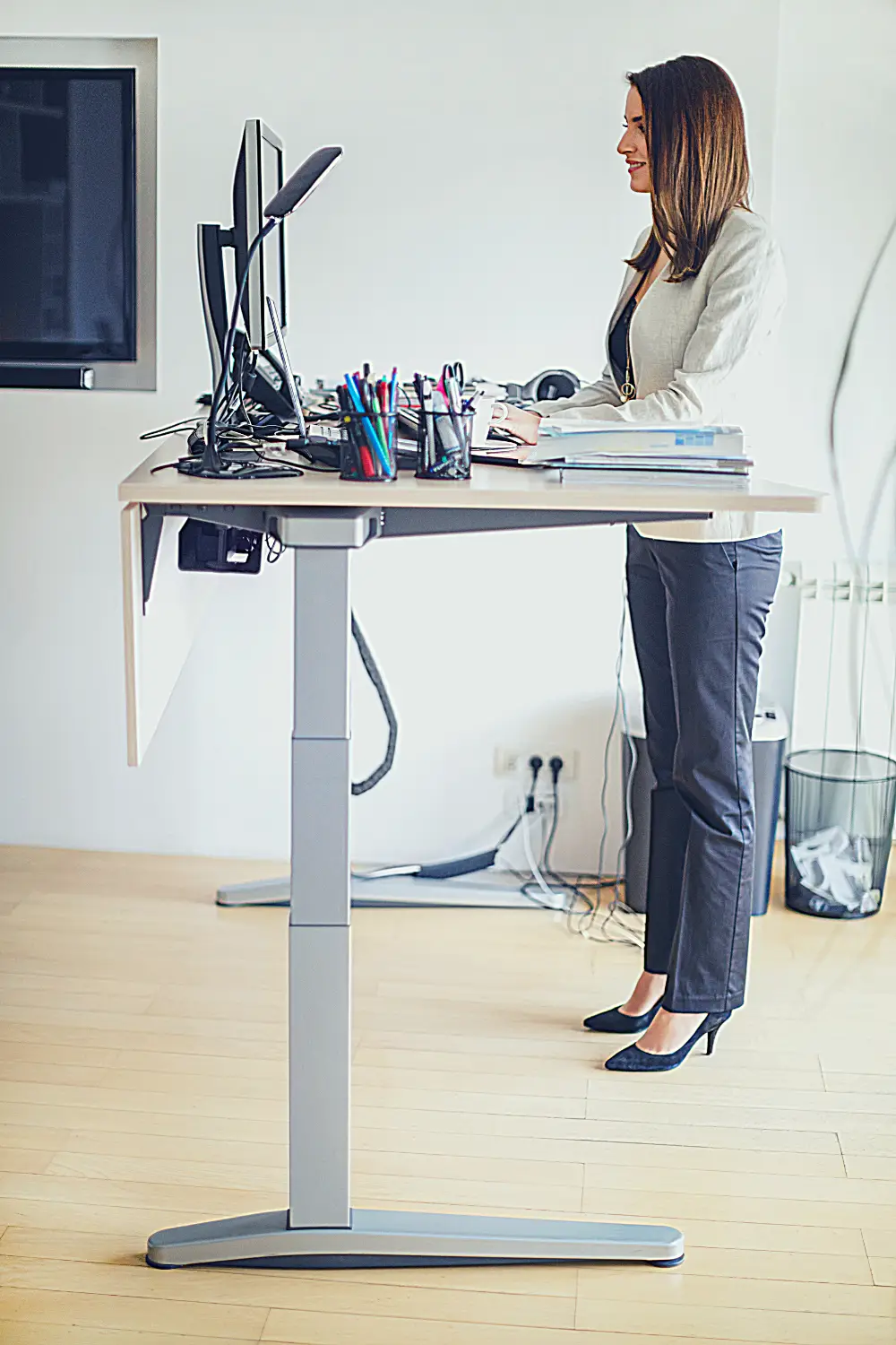 A woman stands in front of a computer at a standing desk