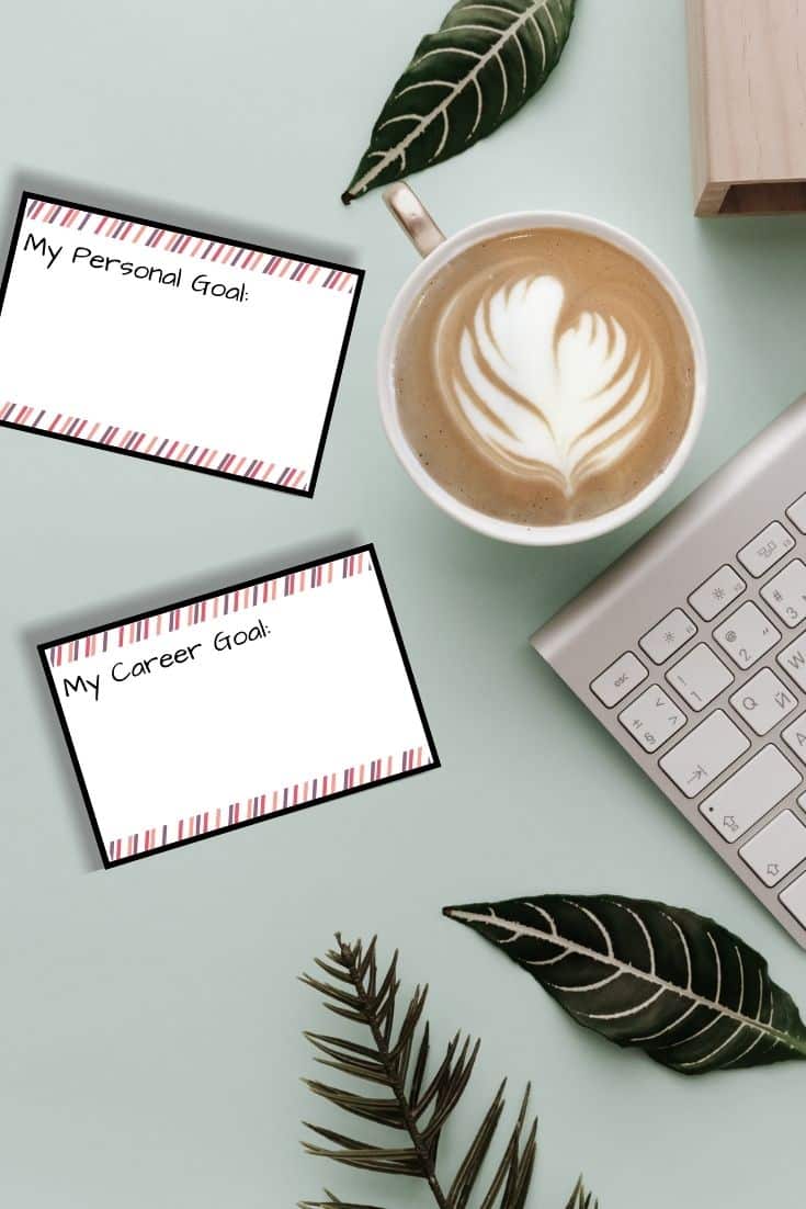 Goal cards lay on a desk next to a cup of coffee and a keyboard