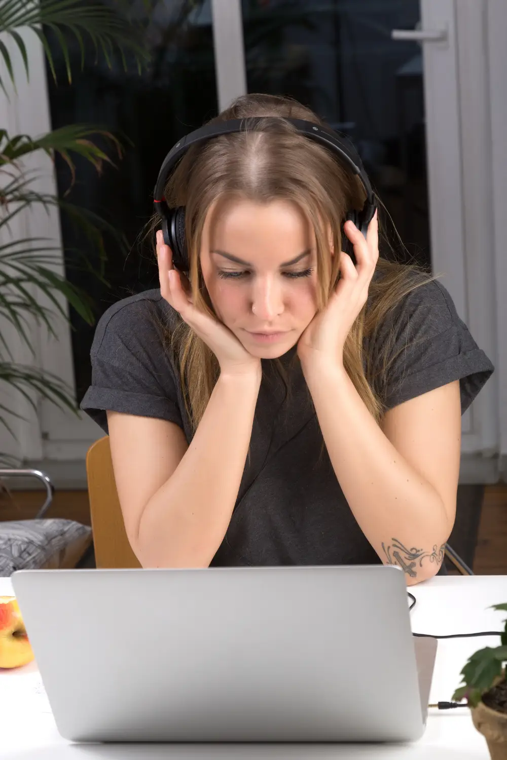A woman listens to music through headphones while looking at her computer