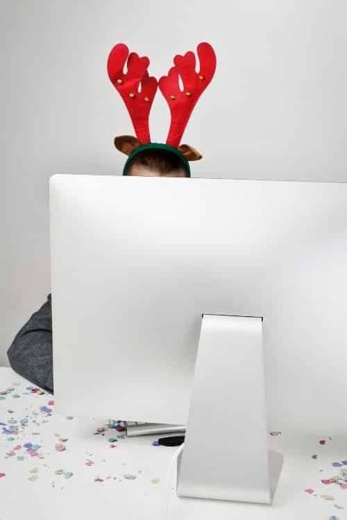 A man wearing reindeer ears sits behind a computer